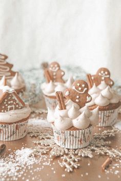 some cupcakes with frosting and gingerbread decorations on them are sitting on a table