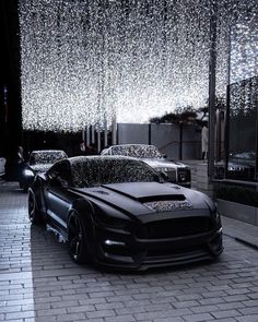 two cars parked in front of a building with rain drops hanging from the ceiling above them