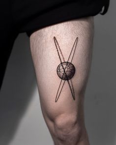 a person with a tattoo on their leg that has two crossed swords and a globe