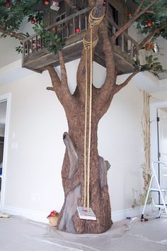 a tree house built into the side of a tree in a room with white walls