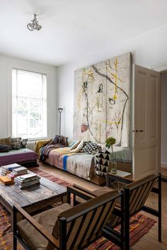 a living room filled with furniture and a large painting on the wall above it's headboard