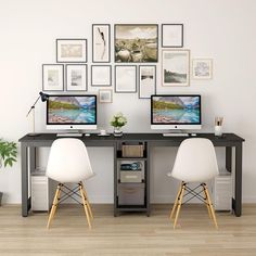 two computers sitting on top of a wooden desk in front of a wall with pictures