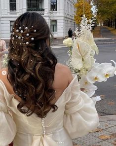 the back of a woman's head with flowers in her hair and pearls on it