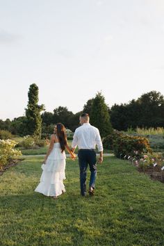 a bride and groom holding hands walking through the grass