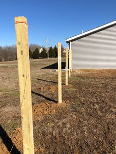 some wooden posts in the dirt near a building