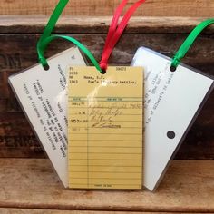 two pieces of paper with red, green and yellow ribbons hanging from them on a wooden bench