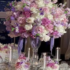 a tall vase filled with lots of purple and white flowers sitting on top of a table