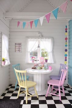 two colorful chairs sitting at a table in a room with white walls and black and white checkered floor