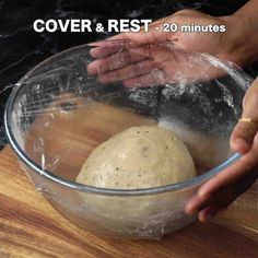 a person is kneading dough in a bowl on top of a wooden table