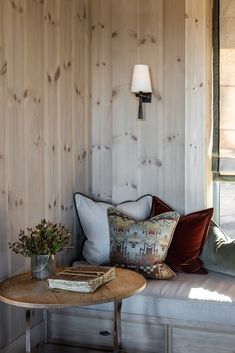 a living room with wood paneling and pillows on the couch next to a coffee table