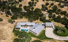 an aerial view of a home in the middle of a field with trees and grass