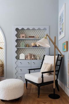 a white chair sitting in front of a book shelf next to a footstool