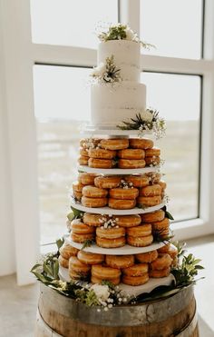 a three tiered wedding cake with donuts stacked on each layer and greenery