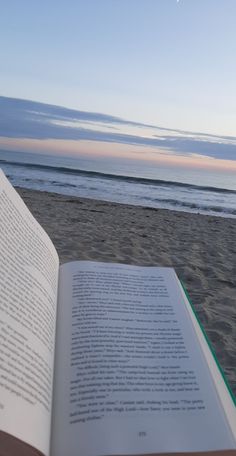 an open book sitting on top of a sandy beach