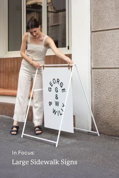 a woman standing next to a white sign