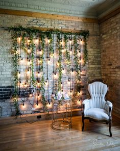 a white chair sitting in front of a brick wall covered in vines and lit candles