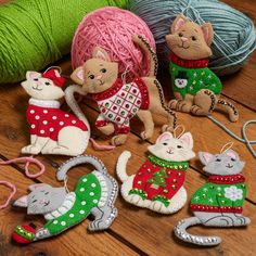 several knitted ornaments are sitting on a wooden floor next to balls of yarn and knitting needles