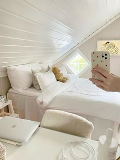 a person taking a photo of a bed in a room with white walls and ceilings