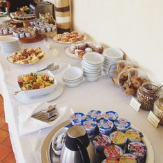 an assortment of food on a table with plates and cups in front of the buffet