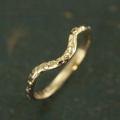 a wedding ring with an intricate design on the outside and inside, sitting on a black surface