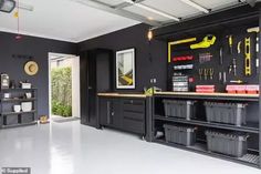 a garage with black cabinets and tools hanging on the wall