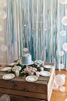 a table topped with lots of plates and cake next to a wall covered in streamers