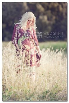 a woman standing in tall grass with her back to the camera