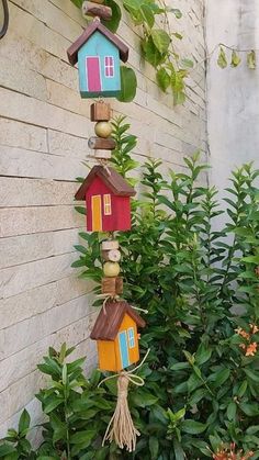 several bird houses are hanging from the side of a building in front of some bushes