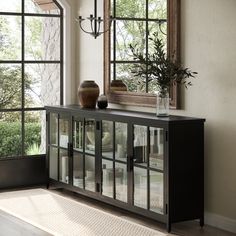 a black cabinet with glass doors and vases on top