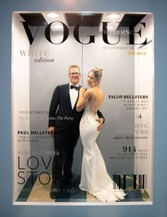 a man and woman posing in front of a magazine cover for a wedding dress store