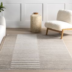 a living room area with two chairs and a rug on the floor in front of a white wall