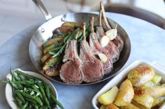 some meat and vegetables are in bowls on a table with silverware next to them