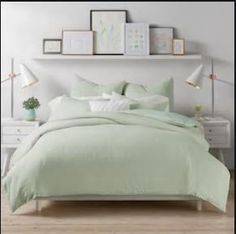 a bedroom with white walls and light green comforter on the bed, along with two nightstands