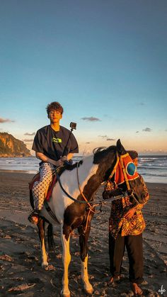 a man riding on the back of a brown and white horse next to another person