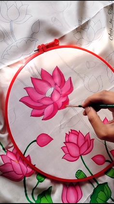 a person is using a needle to draw flowers on fabric