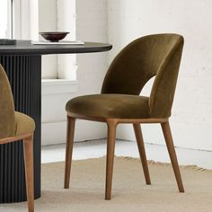 two chairs sitting next to each other in front of a round table with a bowl on it