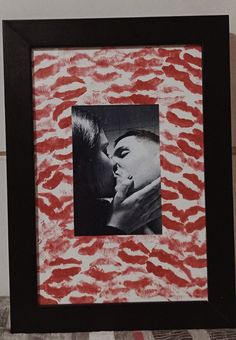 a black and white photo with red lipstick on the wall next to a framed photograph