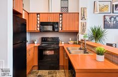 a kitchen with wooden cabinets and black appliances in the center, along with pictures on the wall