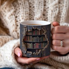 a woman holding a coffee mug with a book shelf on it's side and a ring in her hand