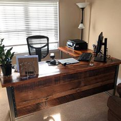 a wooden desk with a computer on it in front of a window and a chair