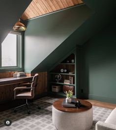 an attic office with green walls and wood paneled ceiling, leather chair, coffee table, bookshelf, and built - in shelving