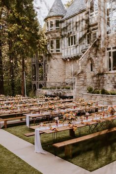 tables set up in front of an old building for a formal dinner or reception with flowers and greenery