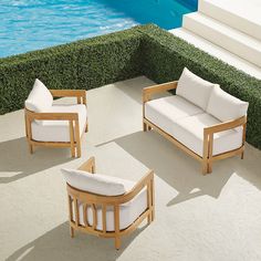 three wooden lounge chairs sitting next to a swimming pool