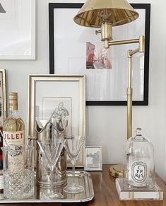 a table topped with bottles and glasses on top of a wooden table next to framed pictures