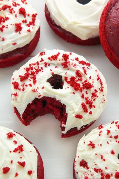 several red velvet donuts with white frosting and sprinkles on them