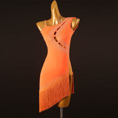 an orange dress with fringes and beads on the shoulders is displayed in front of a black background