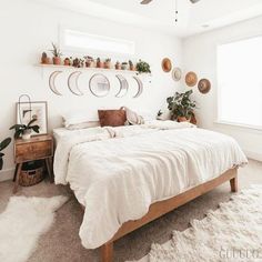 a bedroom with white walls and lots of potted plants on the shelves above the bed