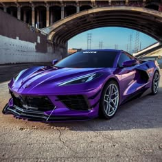 a purple sports car parked in front of a bridge