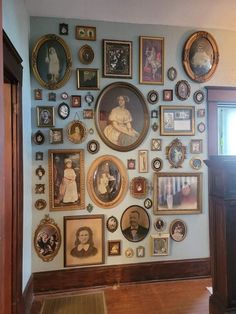 a wall with many different pictures and frames hanging on it's side, along with a wooden door