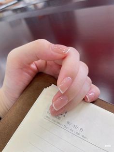 a woman's hand with french manicures on her nails holding a piece of paper